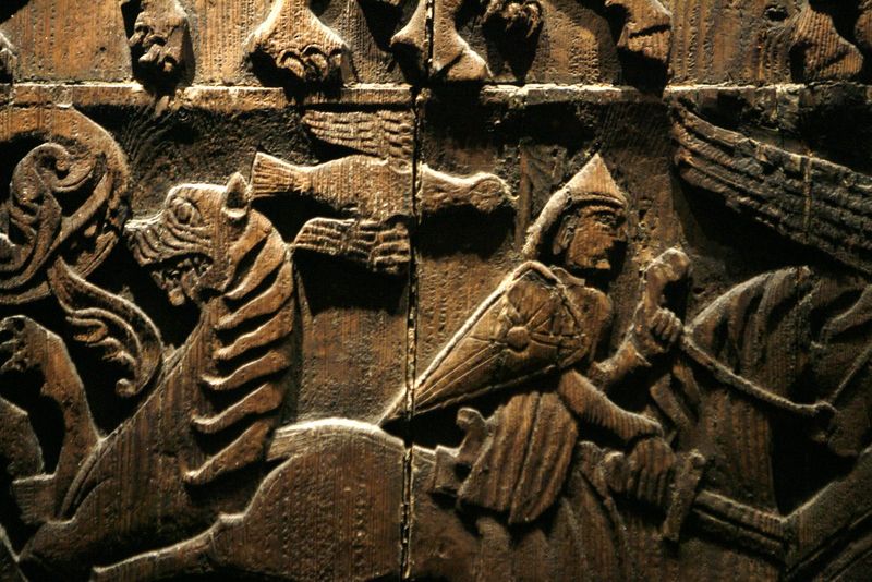Udsnit af et udskåret træpanel med en figur med spids hjelm og ornamenter